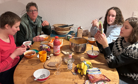 Vier Personen sitzen am Lebensmitteln und Geschirr gedeckt