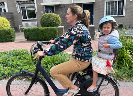 Frau auf E-Hollandrad mit Kind auf Gepäckträger