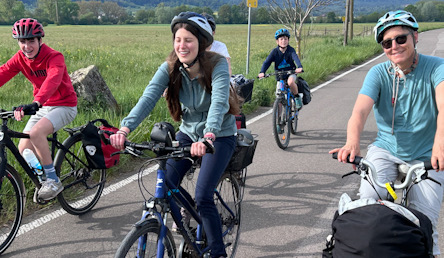 Gruppe von Erwachsenen und Kindern fährt gemeinsam mit Fahrrädern auf einer Landstraße