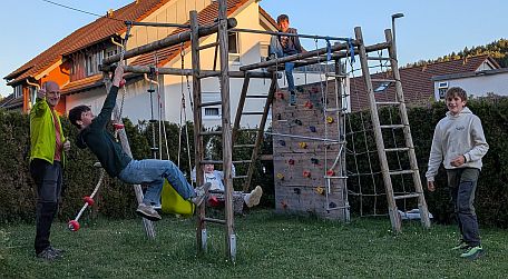 Mehrere Kinder spielen und klettern an einem Spiel- und Klettergerüst im Garten