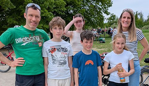 Gruppe von Erwachsenen und Kindern steht im Freien neben Fahrrädern auf einer Wiese