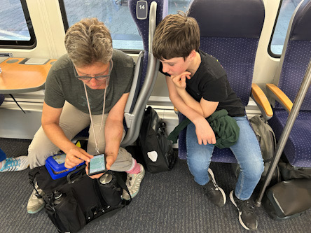Miri und Valentin: Blick aufs Handy im Zug
