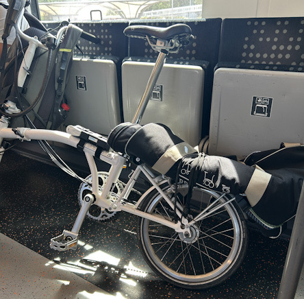 Weißes Brompton mit Transporttasche im Zug